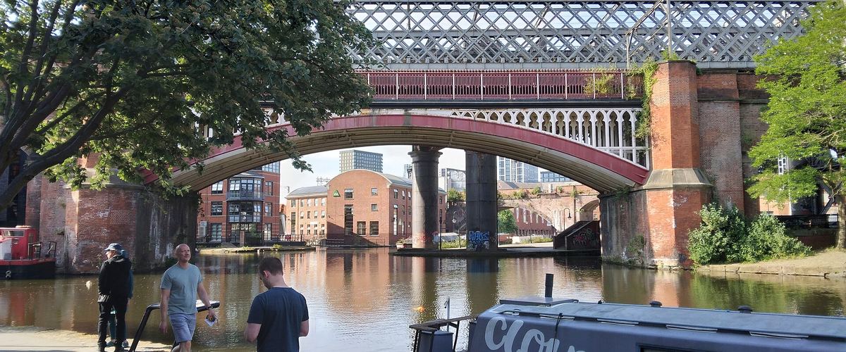 The Bridgewater Canal at Castlefield, Manchester, with people on the towpath and the railway viaducts behind